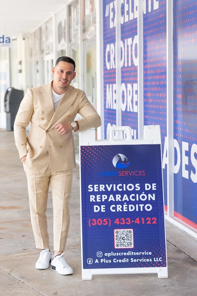 A team member beside the A Plus Credit Services sign outside the Coral Way office